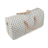 A stylish checkered duffel bag with beige leather straps, ideal for use as weekenders bags, a travel bag, or a gym bag.